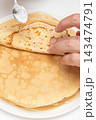 Man spreads sour cream topping on flat round pancake, breakfast morning in cafe 143474791