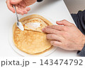 Man spreads sour cream topping on flat round pancake, breakfast morning in cafe 143474792