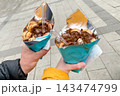 Bubble belgian waffle with chocolate paste in cone, couple hold dessert in hands 143474799