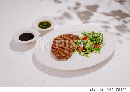 Grilled steak with arugula salad and sauces Grilled steak with arugula salad and sauces 143476122