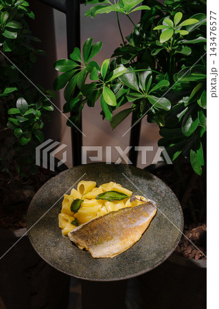 Pan-fried fish fillet with pasta on stone plate Pan-fried fish fillet with pasta on stone plate 143476577