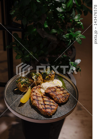 Grilled steak with baked potatoes and lemon wedge Grilled steak with baked potatoes and lemon wedge 143476578