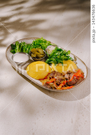 Mamaliga cornmeal dish with meat stew and pickles 143476636