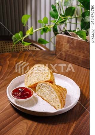 Croissant halves with strawberry jam on a wooden table 143476760