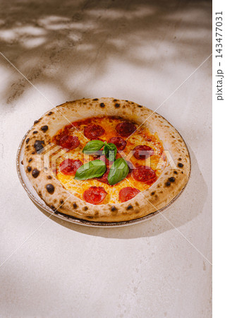 Neapolitan pepperoni pizza with fresh basil on stone 143477031