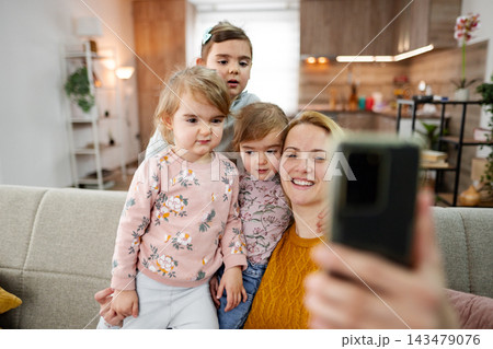 Mother and her three little daughters taking selfies at home Mother and her three little daughters taking selfies at home 143479076