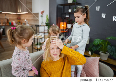 Three little girls are doing their mom's hair Three little girls are doing their mom's hair 143479077