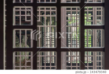 Framed by the intricate geometric lattice of traditional Chinese screens, soft light filters into a quiet interior at Dazu. The interplay of shadow, texture, and dark timber craftsmanship evokes the Framed by the intricate geometric lattice of traditional Chinese screens, soft light filters into a quiet interior at Dazu. The interplay of shadow, texture, and dark timber craftsmanship evokes the 143479340