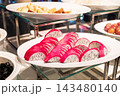 Sliced pink dragon fruit with white flesh and black seeds on plate at restaurant food counter, hotel breakfast buffet 143480140