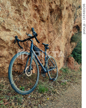 Modern Blue Road Bike Leaning Against Rugged Orange Limestone Cliff. 143480206