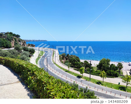 Scenic Panoramic High-Angle View of a Winding Coastal Road and Steep Cliffs over a Deep Blue Sea. 143480209