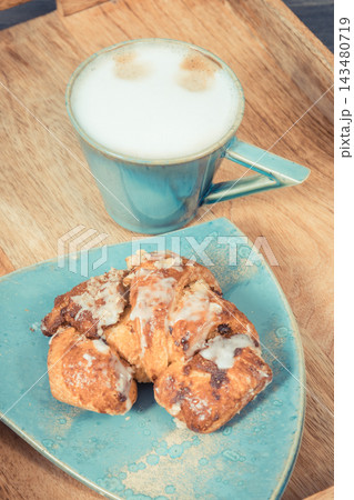Fresh pastry with poppy seed filing on rustic light blue plate, cup of coffee. 143480719