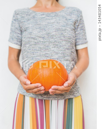 Female holding a pumpkin, presenting a simple autumn harvest and Halloween lifestyle concept. 143481054