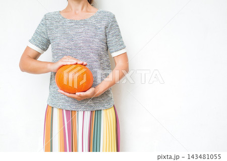 Person holding an pumpkin against white, creating a clean autumn and Halloween concept. 143481055