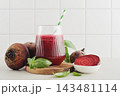 Beetroot juice in a glass with a striped paper straw, served with raw beetroot and fresh basil 143481114