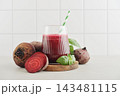 Beetroot juice in a glass with a striped paper straw, served with raw beetroot and fresh basil 143481115