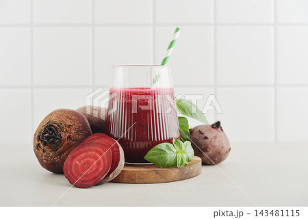 Beetroot juice in a glass with a striped paper straw, served with raw beetroot and fresh basil Beetroot juice in a glass with a striped paper straw, served with raw beetroot and fresh basil 143481115