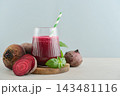 Beetroot juice in a glass with a striped paper straw, served with raw beetroot and fresh basil 143481116