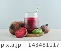 Beetroot juice in a glass with a striped paper straw, served with raw beetroot and fresh basil 143481117