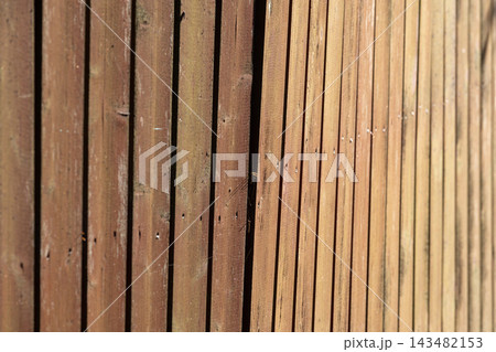 Sunlit wooden fence photographed close up showing vertical slats Sunlit wooden fence photographed close up showing vertical slats 143482153