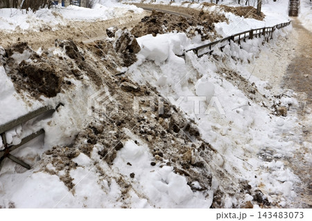 Gritty, towering snowbanks from recent road clearing bury a roadside guardrail, showcasing winter's aftermath and urban infrastructure management Gritty, towering snowbanks from recent road clearing bury a roadside guardrail, showcasing winter's aftermath and urban infrastructure management 143483073