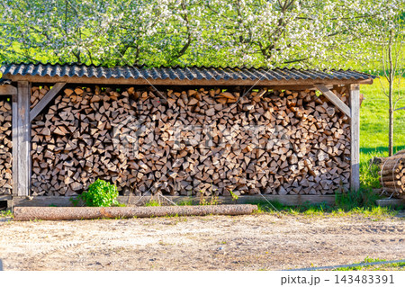 Neatly stacked firewood stored in rustic outdoor wooden shelter 143483391