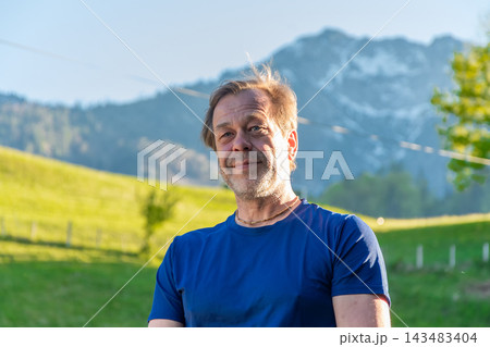 Smiling middle aged man standing outdoors with mountains behind him Smiling middle aged man standing outdoors with mountains behind him 143483404