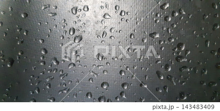 Macro view of water droplets on a dark textured hydrophobic surface. Macro view of water droplets on a dark textured hydrophobic surface. 143483409