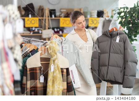 Young woman chooses sweater in clothing store 143484180