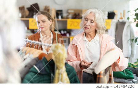 Elderly and young woman choosing outerwear in store 143484220