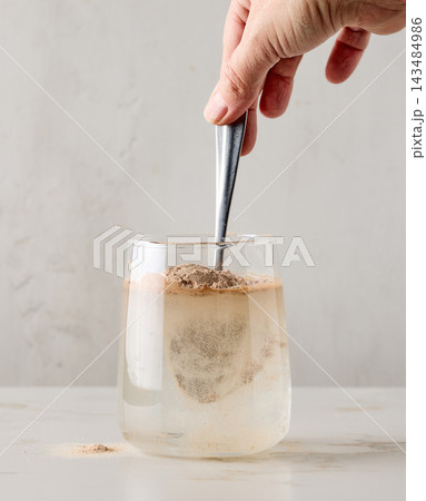 Close up of protein powder added and stirred with spoon in glass 143484986