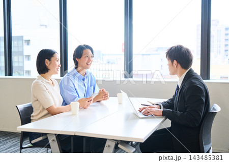 明るいオフィスで不動産の部屋探しを相談する若い夫婦と担当者 明るいオフィスで不動産の部屋探しを相談する若い夫婦と担当者 143485381