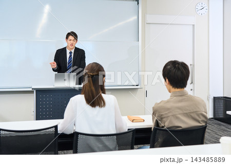教室で熱心に講義を行うスーツ姿の男性講師と受講生 143485889