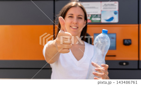 Woman presenting recyclable bottle at collection machine. 143486761