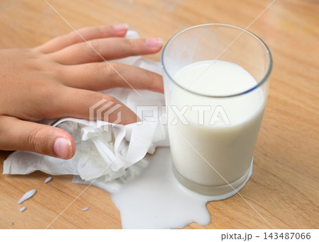 こぼれた牛乳をティッシュで拭き取る子供の手元の様子 こぼれた牛乳をティッシュで拭き取る子供の手元の様子 143487066