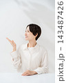手を差し出して案内する笑顔の女性 143487426