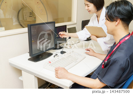 CT検査の画像をチェックする日本人女性ドクターと男性検査技師 CT検査の画像をチェックする日本人女性ドクターと男性検査技師 143487500