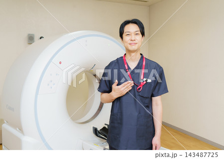 CTスキャンの機械の前に立つ日本人男性検査技師 CTスキャンの機械の前に立つ日本人男性検査技師 143487725