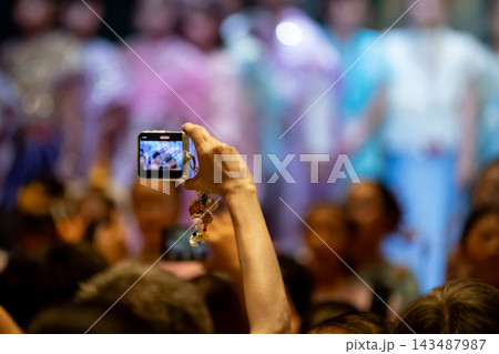 Parents recording their children school performance with smartphones, audience engagement at a school event Parents recording their children school performance with smartphones, audience engagement at a school event 143487987