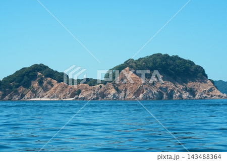 岩肌がむき出しになった緑の小島と青い海 143488364
