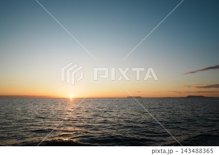 水平線に沈む夕日と群青の空と島影 143488365