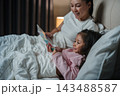 happy mother read story in the book for preschool child girl in bed at night 143488587