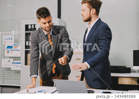 Business team collaborating on digital data analysis in modern office 143490369