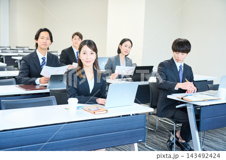 会議室でパソコンを開いて研修を受けるスーツ姿の男女 143492424