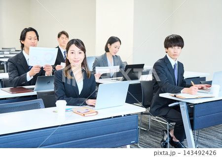 会議室でパソコンを開いて研修を受けるスーツ姿の男女 143492426