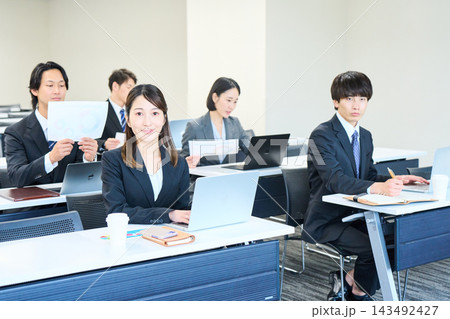 会議室でパソコンを開いて研修を受けるスーツ姿の男女 143492427