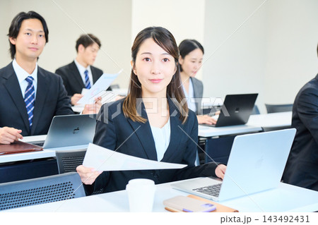 会議室でパソコンを開いて研修を受けるスーツ姿の男女 143492431