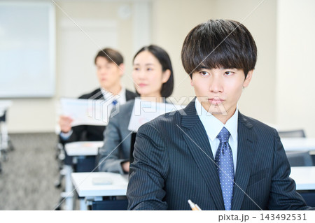 会議室でパソコンを開いて研修を受けるスーツ姿の男女 会議室でパソコンを開いて研修を受けるスーツ姿の男女 143492531