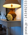 Wedding Bouquet of Cream Roses on a Console Table Beside a Warm Lit Lamp in a Cozy Home Interior 143492533