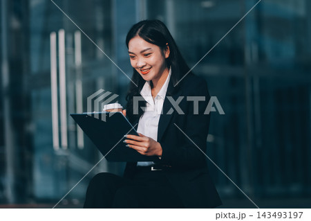Young brunette business lady dressed in black jacket checking work chats sitting outside with laptop Young brunette business lady dressed in black jacket checking work chats sitting outside with laptop 143493197